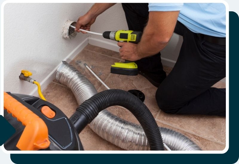 a professional cleaning out a dryer vent with an extension brush and a wet vac
